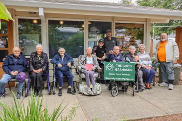 Group of elderly people and caretakers posing outside a care home.