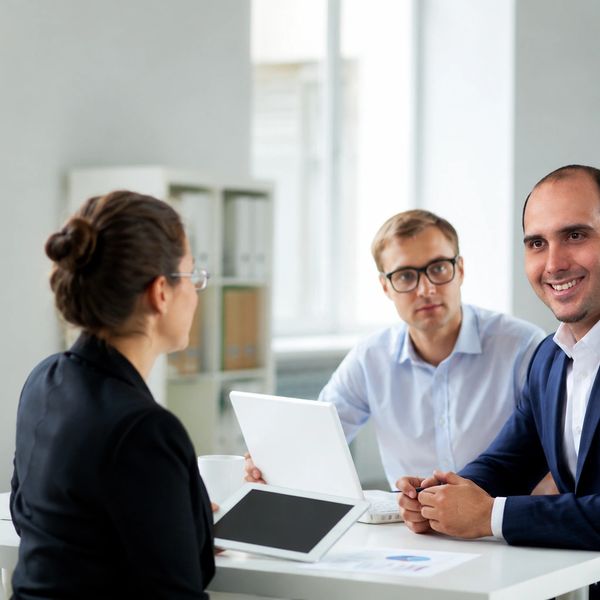 Business meeting with three professionals discussing work around a laptop.