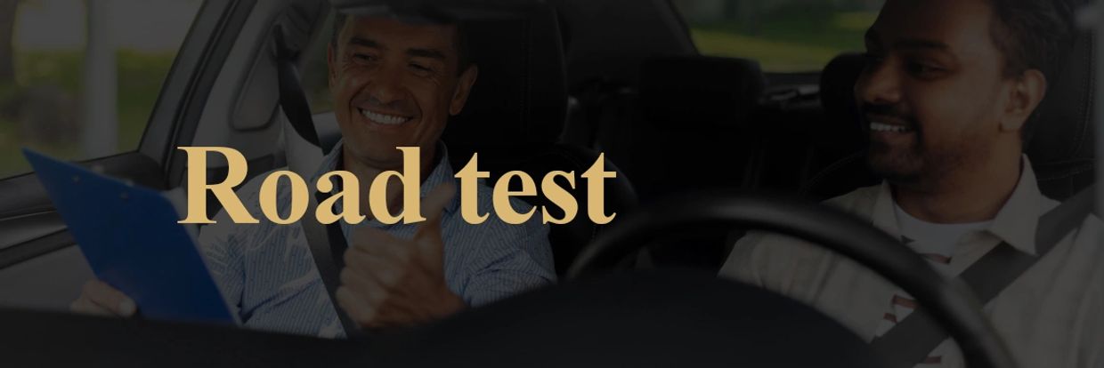 Two men in a car during a road test, one giving a thumbs up.