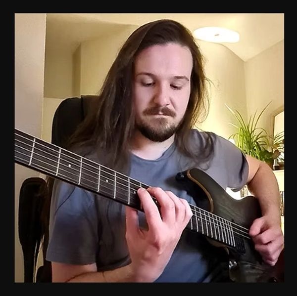Man in deep concentration studying an electric guitar.