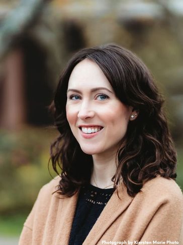 The author, a white woman with dark, wavy hair, flashing a winning smile.