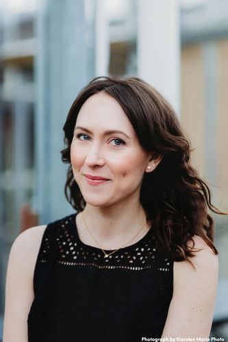 The author, a white woman with dark, wavy hair, smiling gently with a beguiling dimple in one cheek.