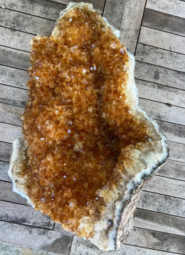 Large orange citrine crystal geode on a wooden surface.
