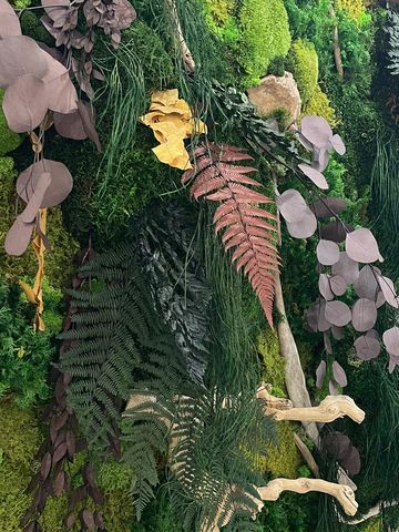 A lush vertical garden wall with diverse green and purple foliage and wooden accents.