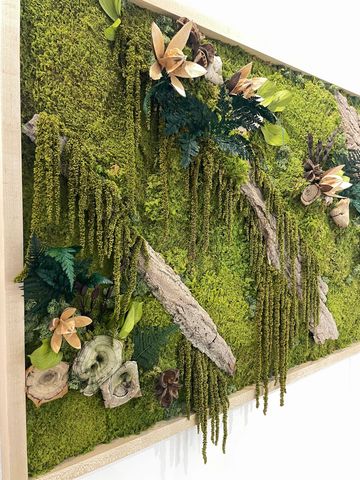 A vibrant green moss wall art with flowers and wood accents.