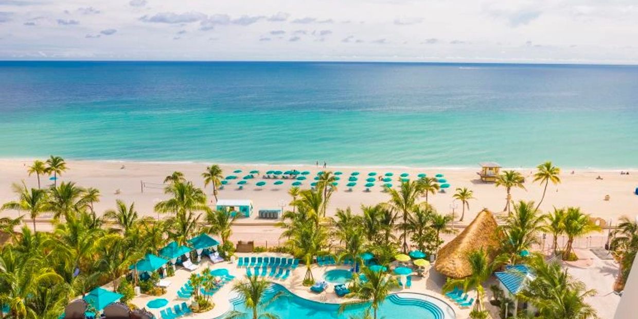 View of a beach resort with umbrellas and a pool.
