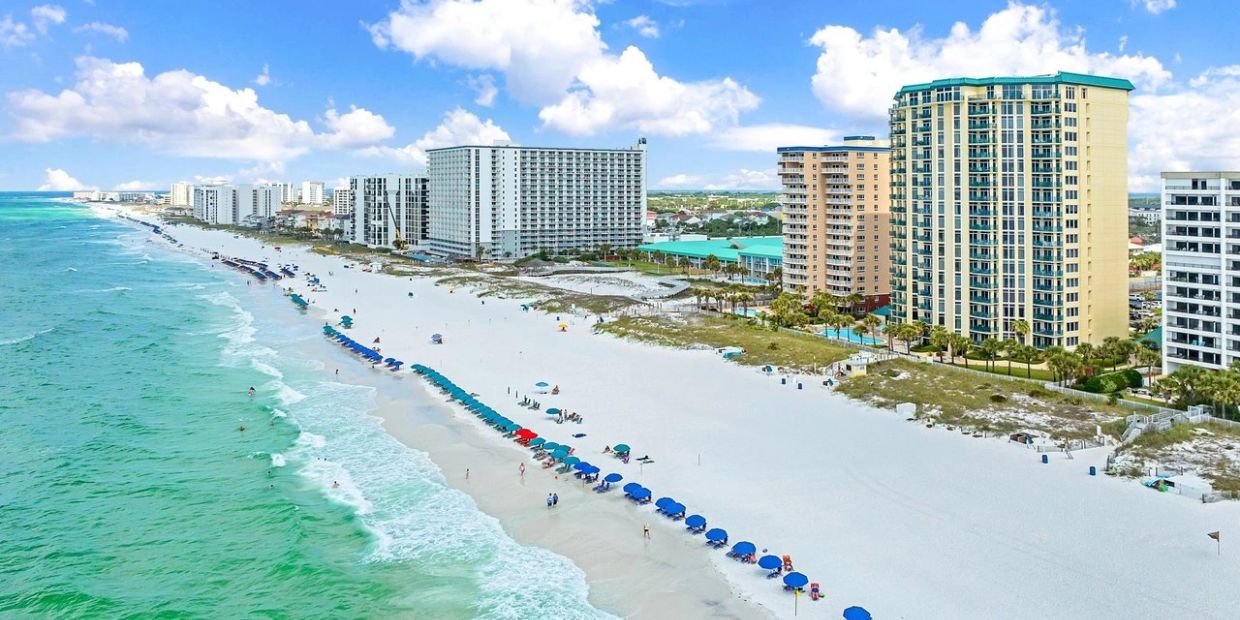 Sunny beach with umbrellas and high-rise buildings.