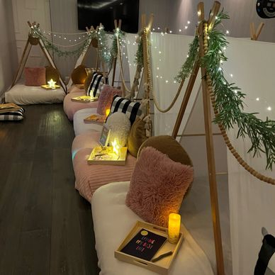 Cozy indoor seating with soft cushions, fairy lights, and personal trays for a relaxing gathering.