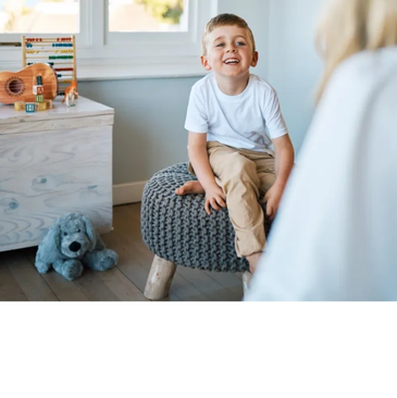 Smiling boy sitting on a knitted stool.