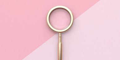 gold magnifying glass on a pink background