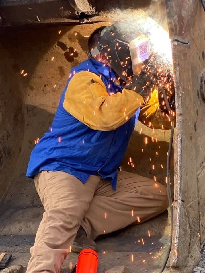 Worker welding metal sparks flying.