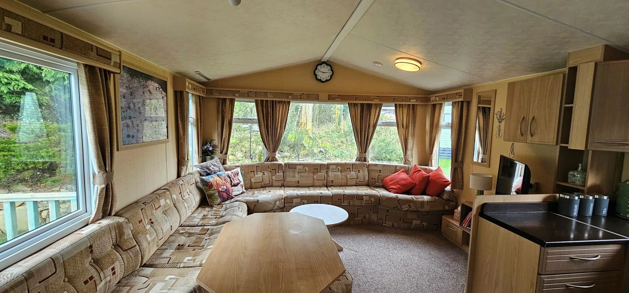 Cozy living area in a caravan with large windows and patterned seating.