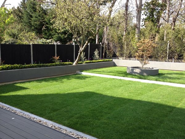 A garden with short grass, trees and decorative stones