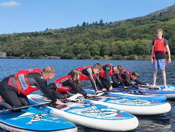 Family and friends stand up paddleboarding in Llanberis, North Wales