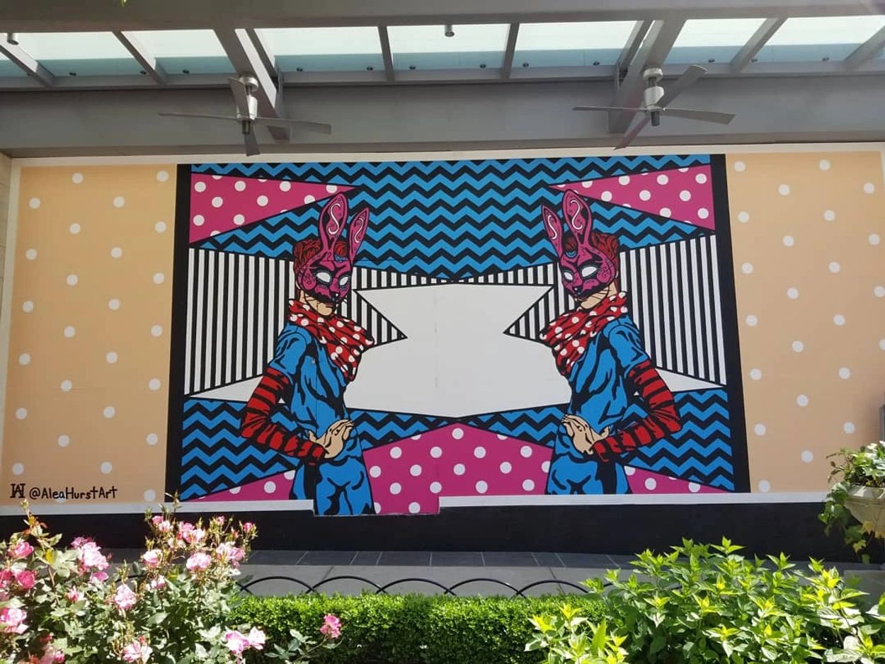 Colorful street art featuring two mirrored figures with bunny masks.