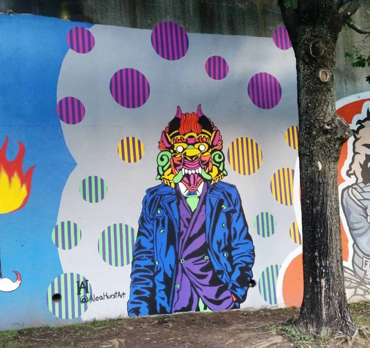 Colorful street art of a figure wearing a demon mask and vibrant clothing.