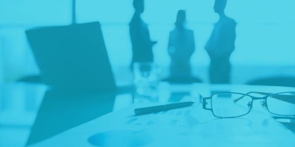 Blurred business meeting scene with focus on glasses and documents.