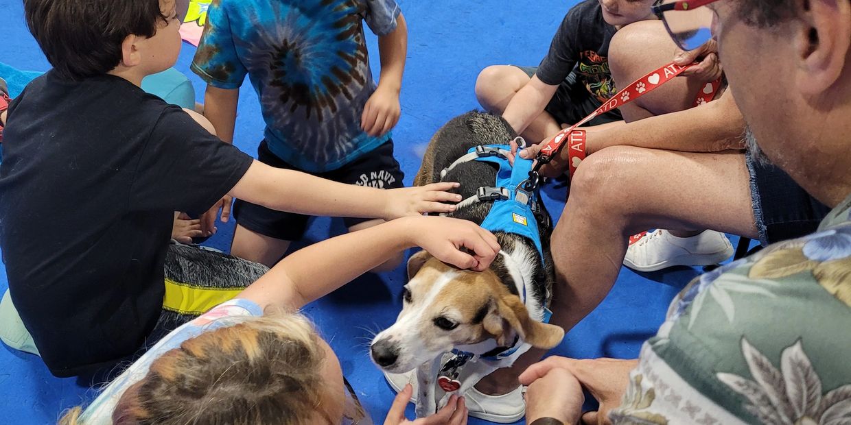 Children and an adult petting a dog on a blue floor.