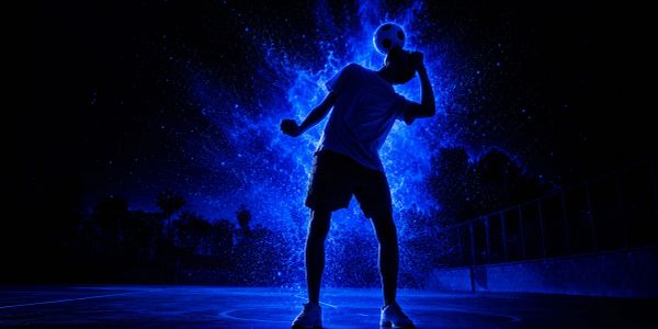 Silhueta brilhante de jogador de futebol em ação à noite.