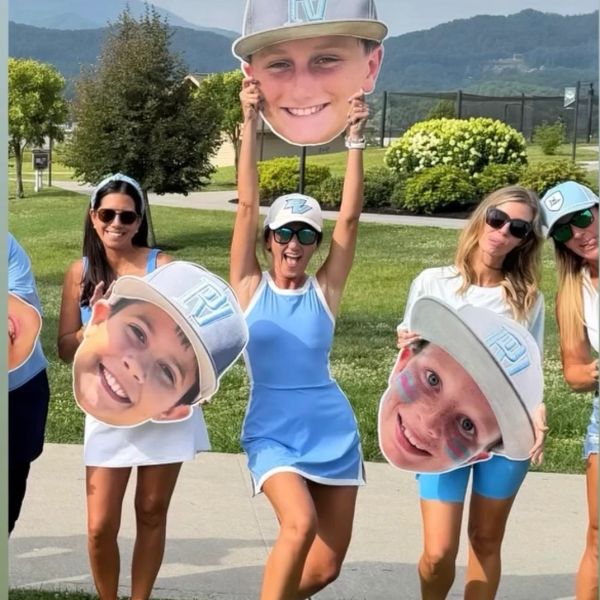 Group holding oversized face cutouts outdoors.