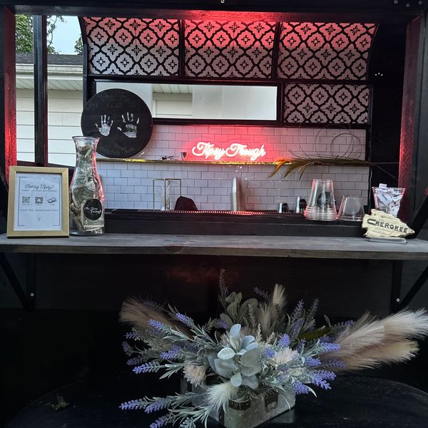 Cozy bar setup with decorative flowers and neon sign.
