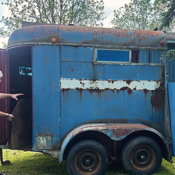 Old, rusty blue horse trailer with peeling paint.