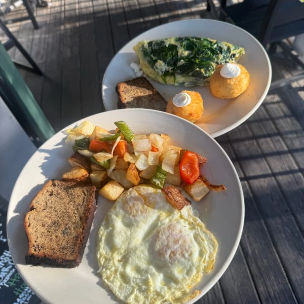 Two plates of breakfast with eggs, toast, and veggies.