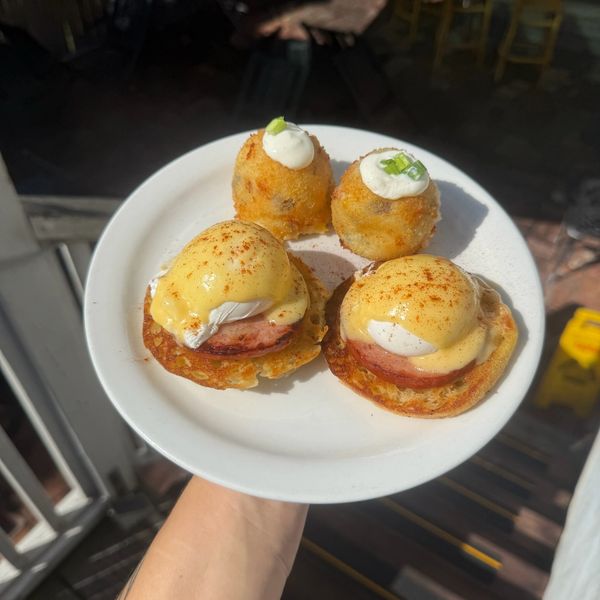 Eggs Benedict with fried sides on a white plate.