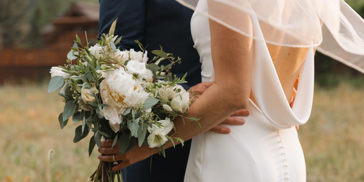 A bride and groom on their wedding day with permanent jewelry as a vendor