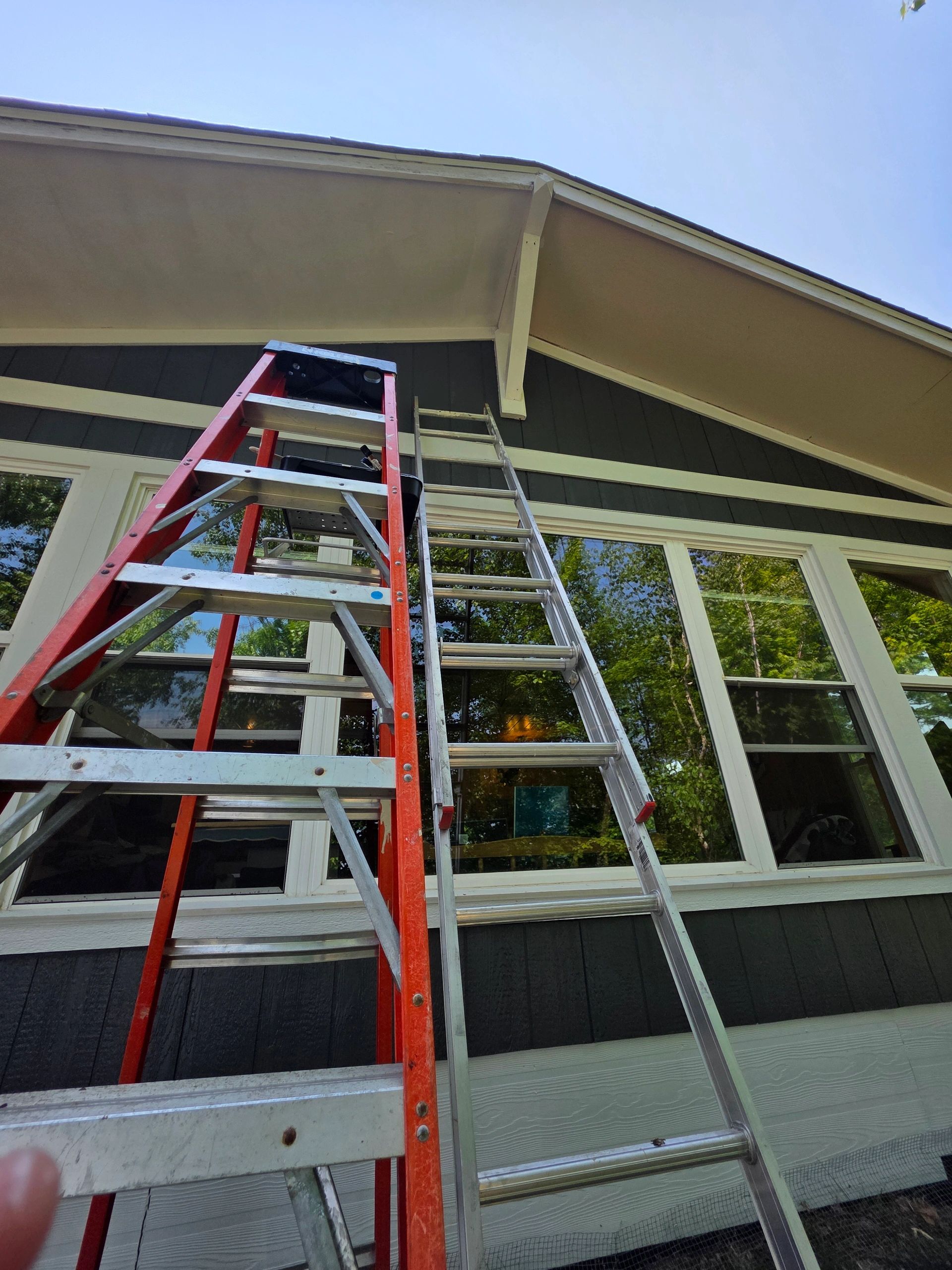 Two ladders leaning against a house under a clear blue sky.
