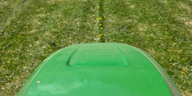 View from a riding lawn mower cutting grass in a backyard.