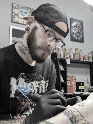 Tattoo artist working intently on a client's arm.