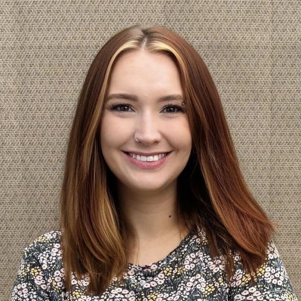 Young woman with a floral shirt smiling at the camera.