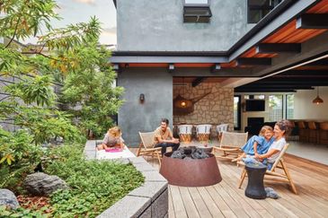 Family enjoying relaxing time in a modern outdoor patio with greenery.
