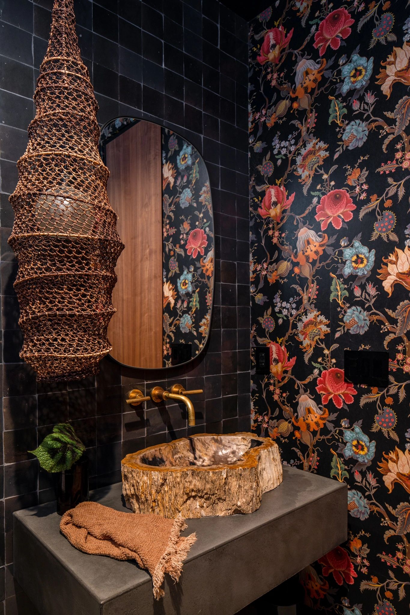 Rustic bathroom with floral wallpaper and wooden sink basin.