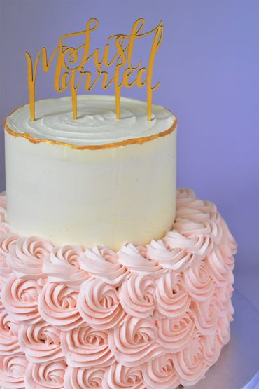 2 tiered wedding cake with pink rosettes and wedding topper