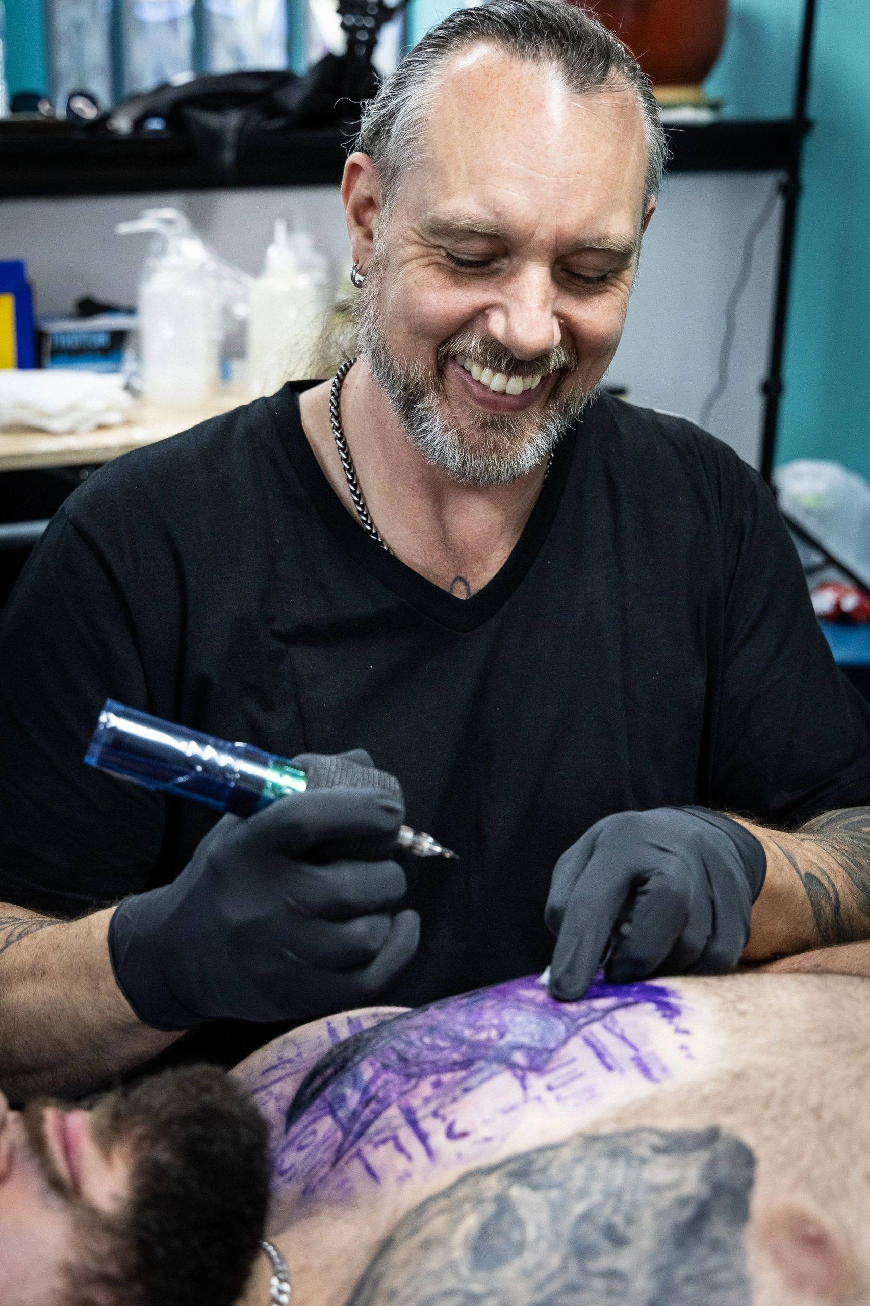 Tattoo artist smiling while working.