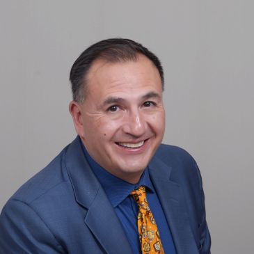 Man in blue suit smiling.