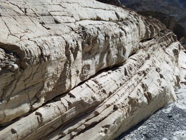 Close-up of layered, cracked rock formations in a dry landscape.