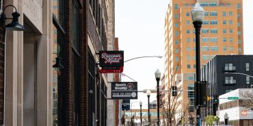Urban street scene with restaurant signs and tall buildings in the background.