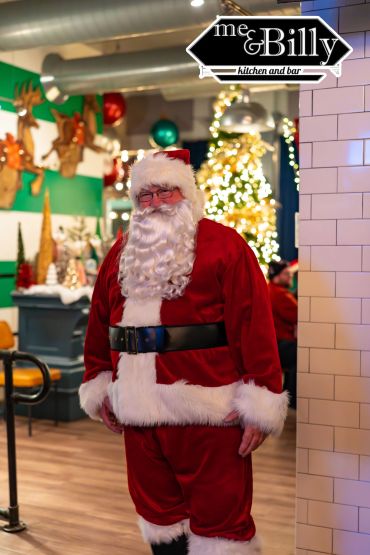 Santa Claus posing inside a festive restaurant.