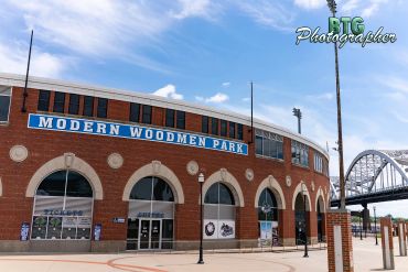 Entrance to Modern Woodmen Park with a clear sky and nearby bridge.