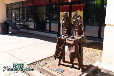 Bronze sculpture of two seated women outside a building.