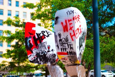 Urban sculpture with graffiti art and colorful tags in an outdoor setting.