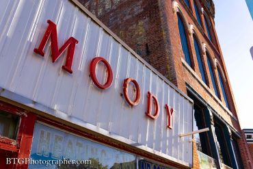 Red "MOODY" letters on a white storefront against a brick building.