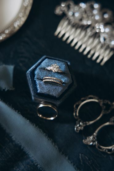 Elegant rings and vintage accessories arranged on a dark fabric.