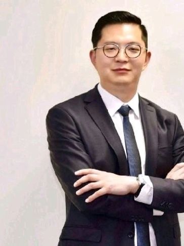 Man in suit with glasses and crossed arms.