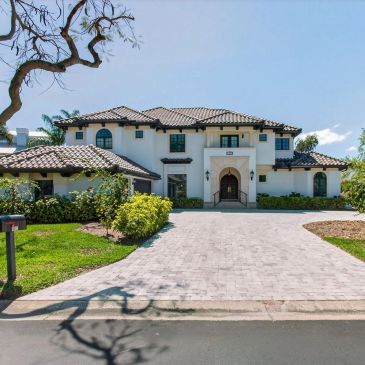Large white house with a tiled roof and paved driveway.