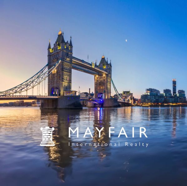 Tower Bridge at dusk over the Thames River with Mayfair Realty logo.