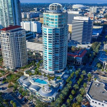 Aerial view of a modern city with tall buildings and palm trees.